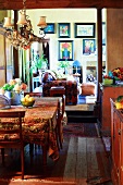 Kitchen dining room in country-house style with colourful pictures on living room wall in background