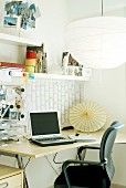 Work station with large paper lampshade above curved desk