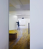 Empty exhibition room with rustic parquet flooring and a man in front of a display wall
