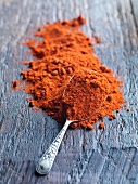 Paprika powder with a spoon on a wooden surface