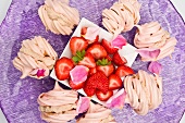 Baisergebäck mit Kastaniencreme gefüllt und frische Erdbeeren auf lila Teller