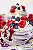 Meringues topped with fresh berries, berry sauce and cream