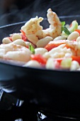 White beans with celery, pepper and prawns in a pan