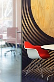 Contemporary office with Eames chair in front of a plywood wall painted with circular shapes (Red Bull Central, Amsterdam)