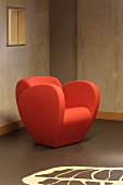 Modern orange armchair in front of a raw concrete wall with patterned floor (Floriande Public Library)
