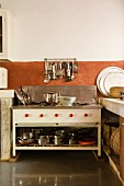 Schlichter Küchenherd mit Kochgeschirr in teilweise offenem Unterschrank vor Wand