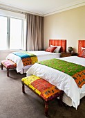 Twin beds with ethnic textiles and matching bedroom benches