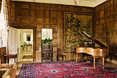 Naturholz Klavierflügel im Musikzimmer mit Kassetten Holzverkleidung an Wand und Blick durch offene Tür in Gang