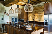 Finnish, designer pendant lamps made from wooden slats above free-standing kitchen counter and cupboards with solid wooden doors in rustic interior