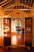 Blick durch offene Türen in Holztrennwand mit Schnitzereien im Rundbogen in traditionellem Wohnhaus