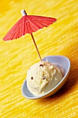 A scoop of peach and mascarpone ice cream decorated with a cocktail umbrella