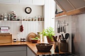 Open shelving and solid oak work surfaces in kitchen with white wooden wall panels