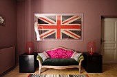 Framed union jack flag above a sofa upholstered in a range of fabrics in bedroom with black chinese lacquer boxes and rugs
