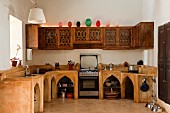 Indische Küche - Gemauerte Küchenzeile mit spitzbogenartigen Öffnungen in Unterschränken und geschnitzte Hängeschränke