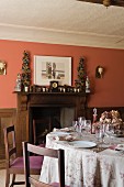 Dining table and wood fireplace in home of fabric designer Richard Smith in East Sussex