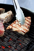 Tongs Flipping Tuna on a Charcoal Grill