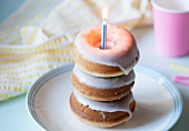 Three Glazed Doughnuts Stacked with a Birthday Candle