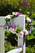 Flower wreath with daisies on a garden bench