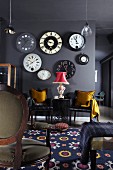 Collection of antique wall clocks on grey wall above elegant leather chairs with golden cushions