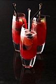 Three red cocktails with blackberries and limes
