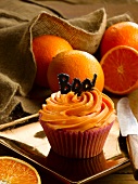 A orange cupcake and fresh oranges