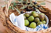 Grüne Oliven in einer Schale und Olivenzweig mit schwarzen Oliven