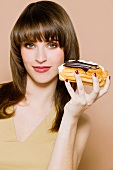 Young woman holding chocolate eclair