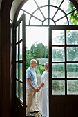 Älteres Paar von einer großen Fenstertür mit Rundbogen