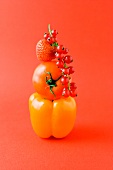 Paprikaschote, Tomate, Erdbeere und rote Johannisbeeren vor orangefarbener Hintergrund