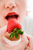 Frau isst eine Erdbeere