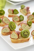 Canapes topped with kiwi and coppa roulade filled with tapenade