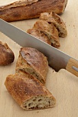 A baguette being sliced diagonally
