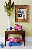 Vase of flowers on antique console table and photos in gilt frame on pastel-green wall