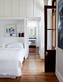 White bedroom with open door and view into ensuite bathroom