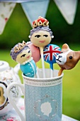 Close up of funny lollies decorated as the Queen, a Union Jack and a corgi in a British tea cup