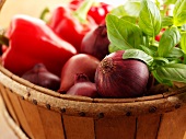 Red onions, peppers and basil in a wooden basket