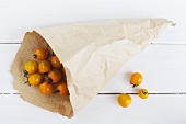 Yellow cherry tomatoes in a paper bag and next to it