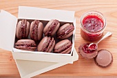 Chocolate macaroons filled with raspberry jam, in a white cardboard box