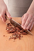 Hands chopping pecan nuts with a large knife