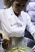 A chef stirring ingredients in a large bowl