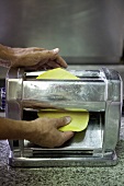 Pasta dough being passed through a pasta machine
