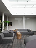 Atrium eines modernen Architektenhauses mit grauer Wohnlandschaft und weißen Einbauschränken mit Hochglanzfronten