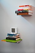 Bücherstapel an weißer Wand hängend, Aufhängung ist unsichtbar