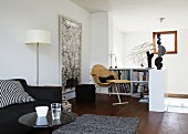 Upholstered sofa and small reading corner with half-height bookcase and Delta armchair in living room