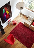 View down into living room with red rug, designer armchair, designer standard lamp and photographic artwork