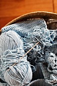 Pale blue crochet work, ball of wool and crochet needle in knitting basket