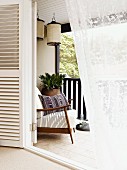 View into comfortable loggia with 50s armchair and lanterns hanging from ceiling in summery ambiance