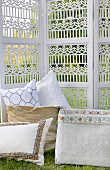 Cushions in baskets in front of carved screen in garden