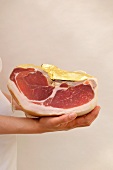 A woman holding a Parma ham wrapped in gold foil