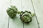 Two artichokes on a wooden surface